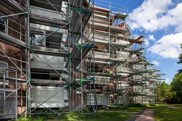 Rückseite eines Gebäudes, welches bei seinen Balkonen in ein Baugerüst gehüllt ist