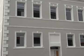 Fassade eines warmgrauen Gebäudes mit schlichten, weißen Details