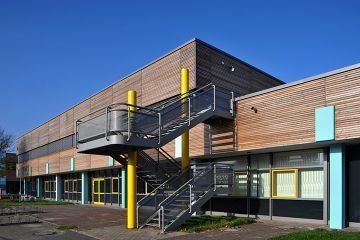 Eine graue Treppe führt auf das Dach des mit Holzpaneelen verkleideten Gebäudes der IGS Wilhelmshaven