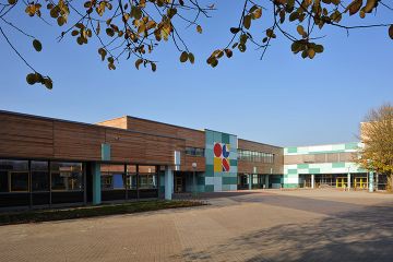 Der große Gebäudekomplex der IGS Wilhemshaven mit einer Fassade in Holzoptik und türkisen Plattenelementen