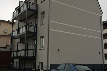 Rückseite eines warmgrauen Gebäudes mit sechs modernen Balkonen